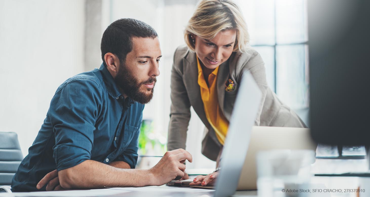 Eine Frau und ein Mann im Arbeitskontext, die gemeinsam an einem Projekt oder einer Idee arbeiten. Sie schauen gemeinsam auf einen Notebook-Bildschirm.